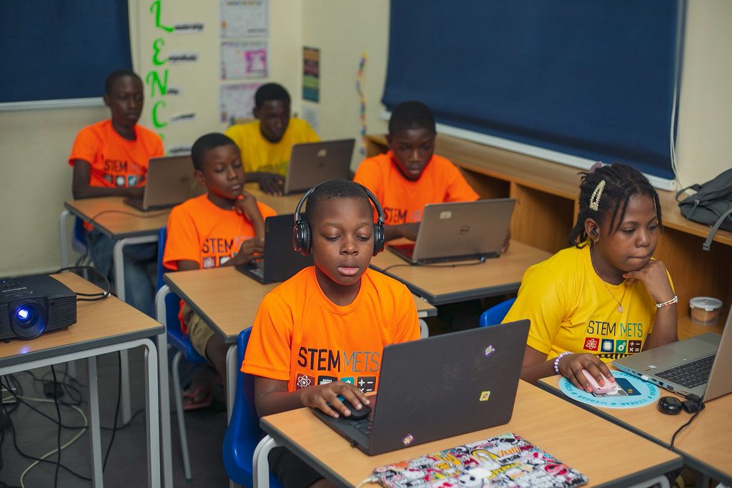 STEM METS learners working through coding challenges on laptops in a bright classroom